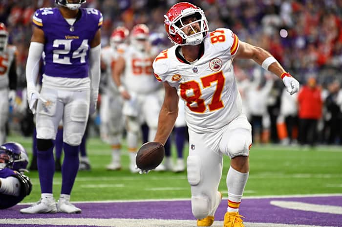 Travis Kelce kneels down with the ball in one hand celebrating a TD in the end zone